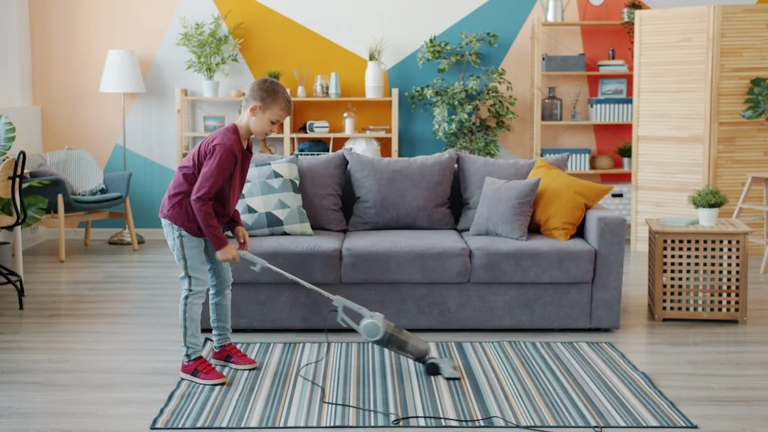 A woman in a gray sweater wipes a table with care, showcasing home cleaning in comfort.